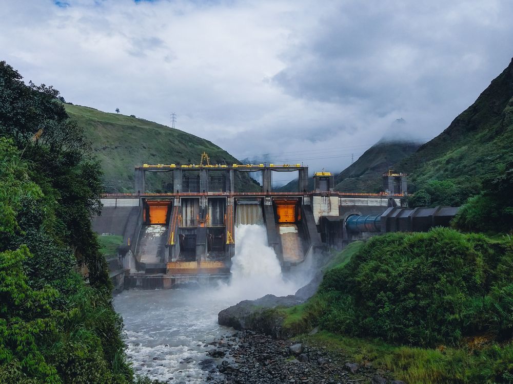 Central hidroeléctrica con vertedero de descarga en un valle de montaña.