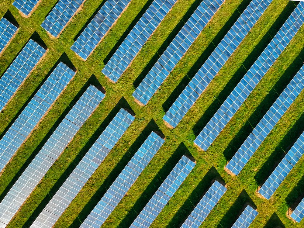 Vista aérea de un parque solar fotovoltaico sobre un campo verde.